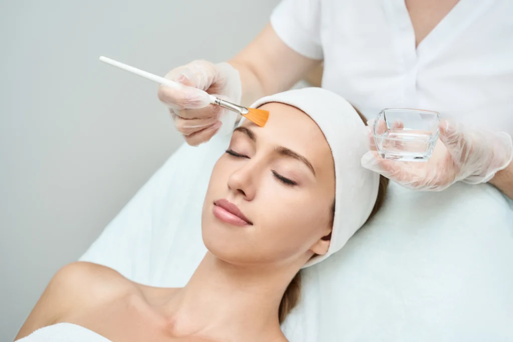 A professional applying a chemical peel solution during a skincare session.