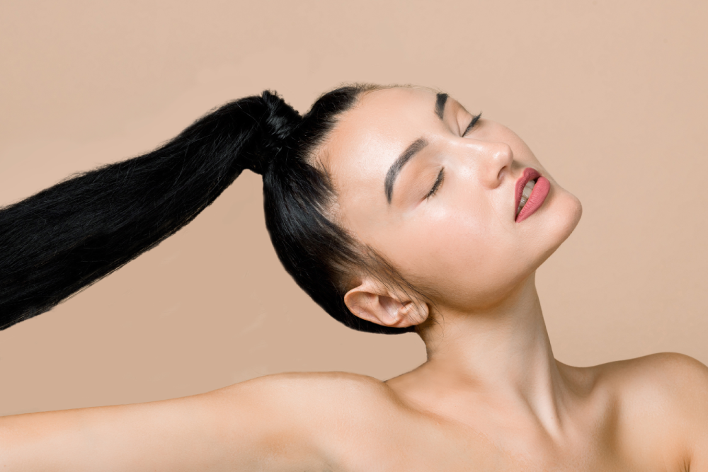 Woman with long ponytail feeling confident after hair restoration.